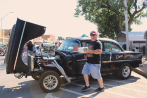 man poses with his classic car at car show