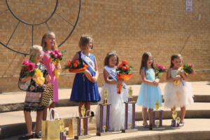 young girls at car show pageant holding flowers and trophies