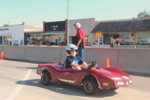 boy driving a race car at car show