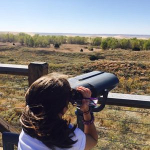 a girl looking through binoculars across the sand dunes