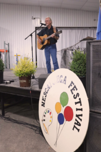 a man playing guitar and singing at an arts festival